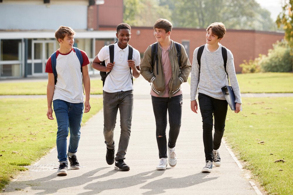 Four diverse students walking together on campus, smiling and chatting.