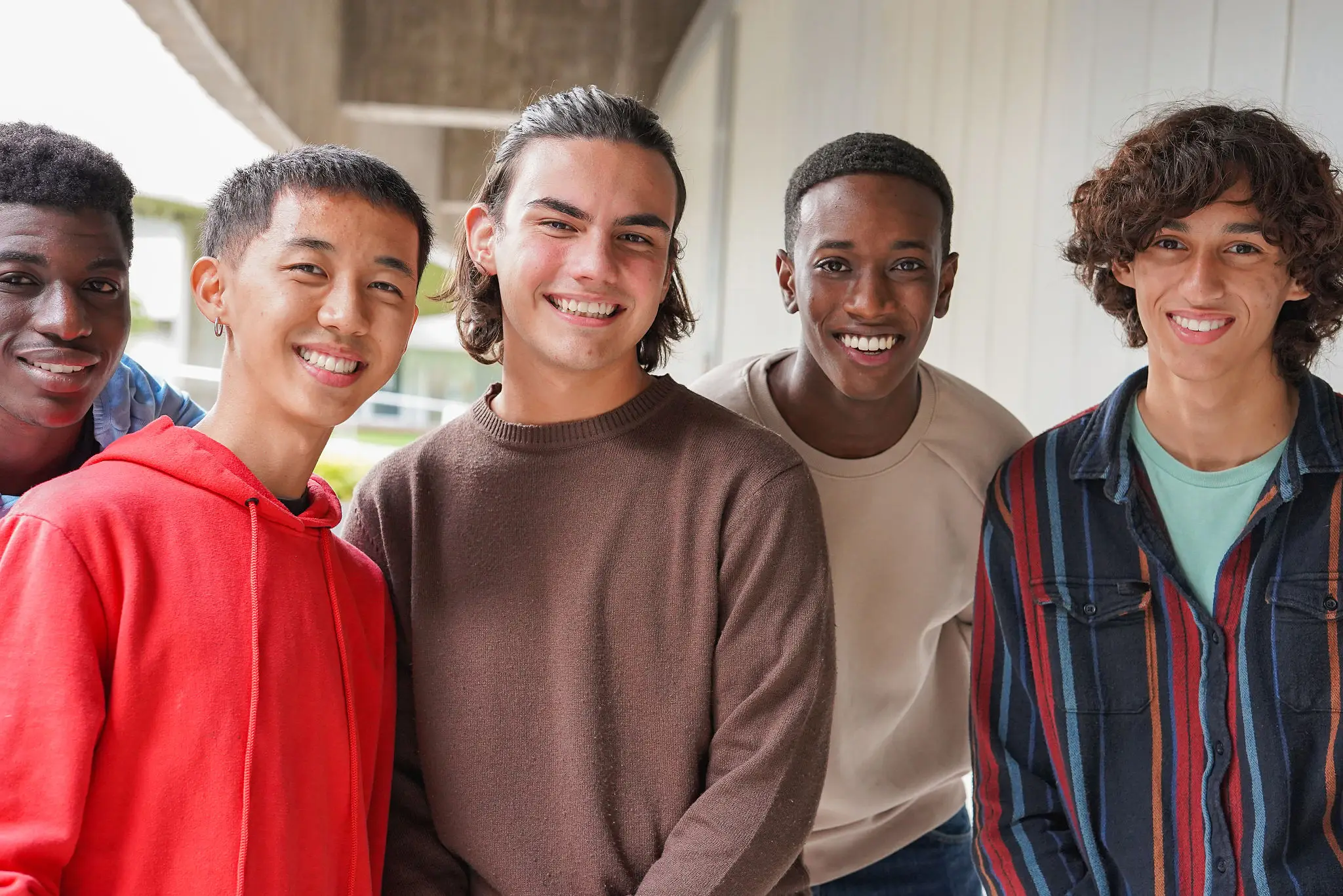 Four teenage boys smiling and standing close together.