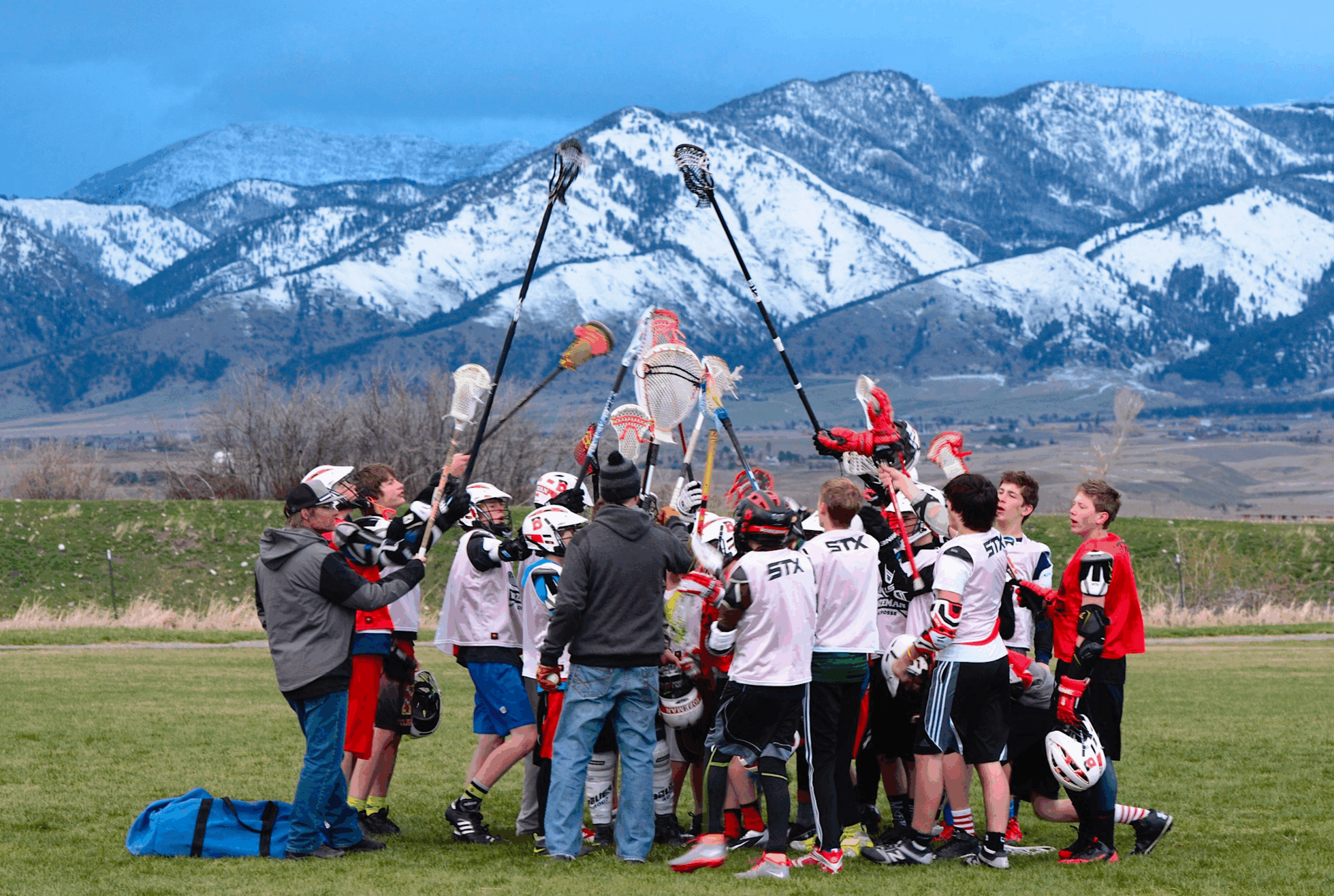 Youth soccer team celebrating victory with mountains in background.