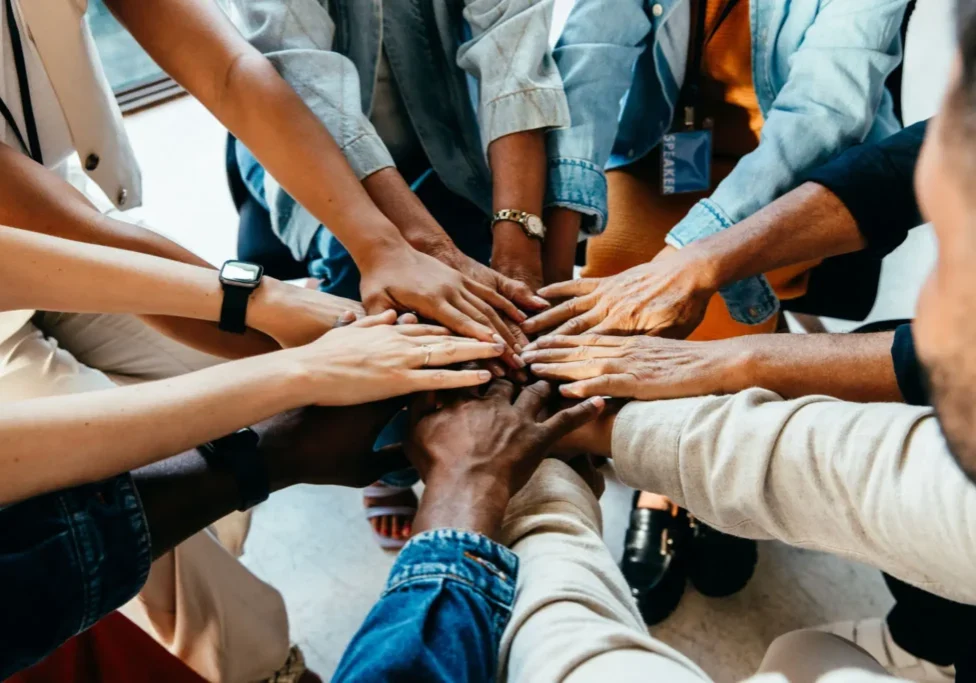 Diverse group joining hands in unity and teamwork.